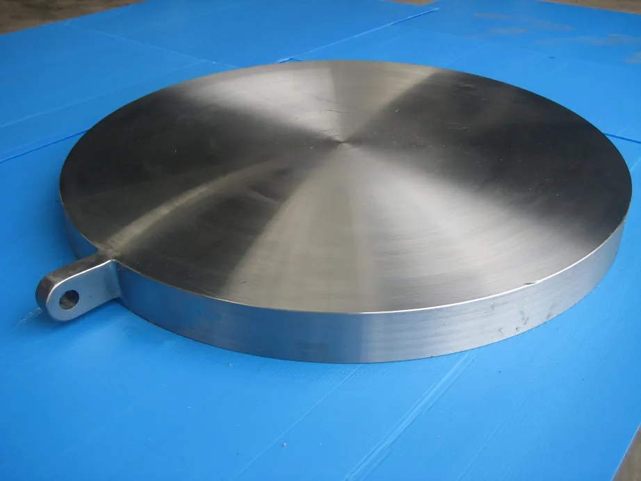A solid machined disc with a single lifting lug on its rim and no bolt holes, on blue sheets