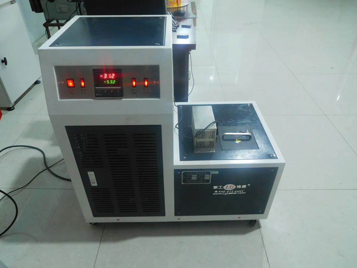 Low-temperature cooling bath cabinet with a red digital temperature display, next to the impact-test area