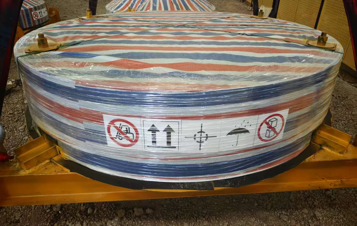 A large flange wrapped in striped woven sheet and stretch film, bolted and strapped onto a yellow steel cradle
