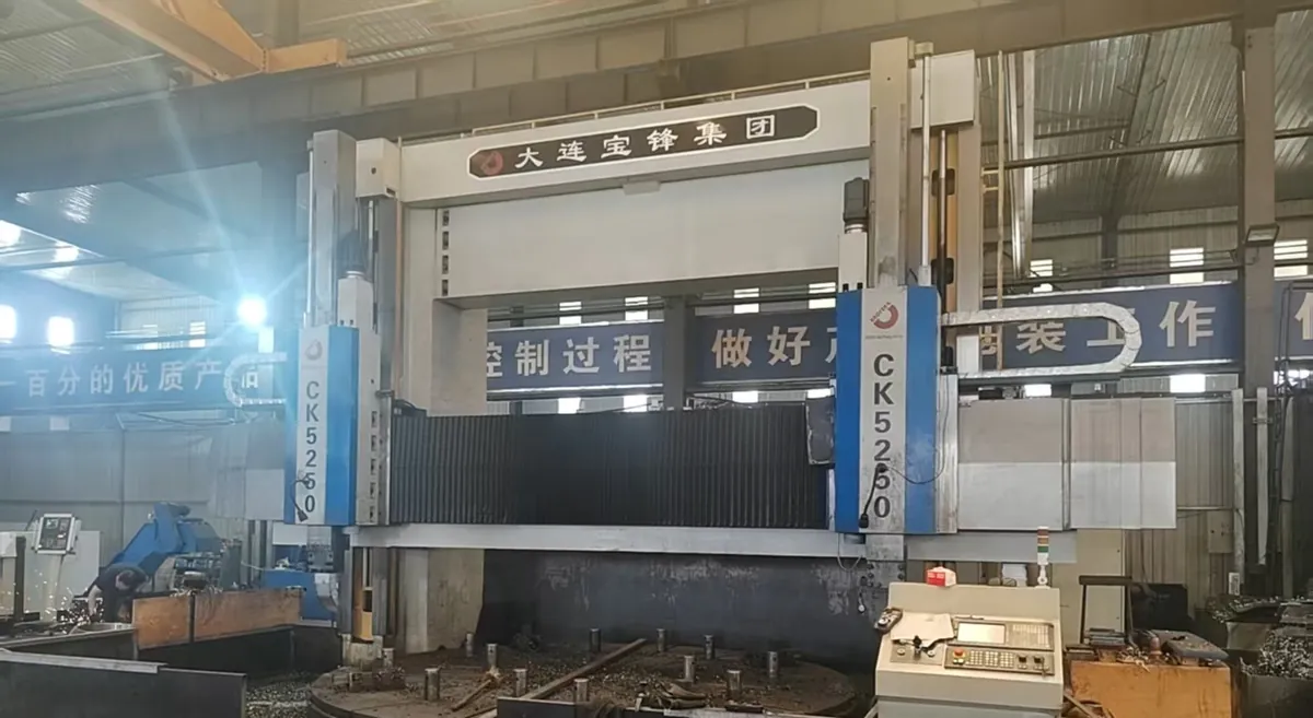 A large double-column CNC vertical lathe with its empty table and control console